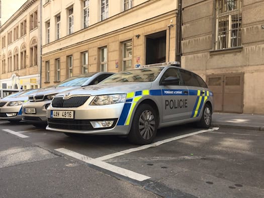 Silberner Škoda-Streifenwagen der tschechischen Polizei mit blau-gelben Markierungen vor einem Gebäude in Prag.