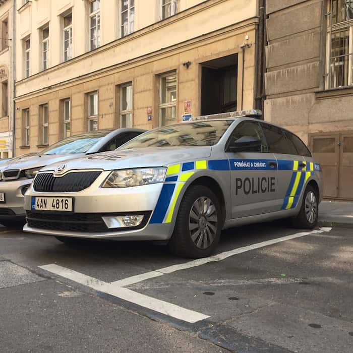 Silberner Škoda-Streifenwagen der tschechischen Polizei mit blau-gelben Markierungen vor einem Gebäude in Prag.