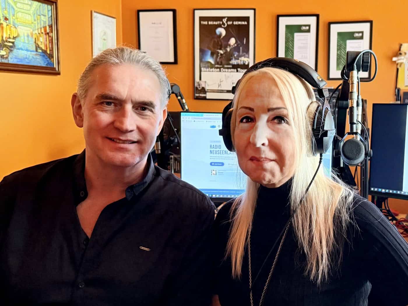 Moderator Thorsten Weickert und Geschäftsführerin Angelika Pörsch (mit Kopfhörern) sitzen nebeneinander im Radiostudio. Im Hintergrund sind Mikrofone, Mischpulte und Computerbildschirme mit dem Logo von Radio Neuseenland zu sehen.