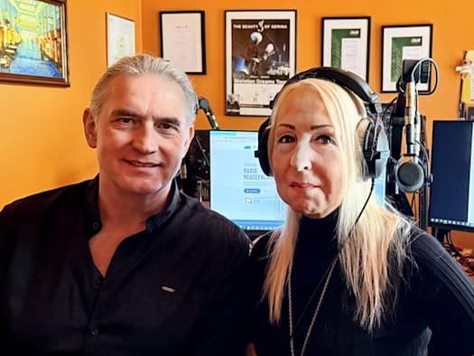 Moderator Thorsten Weickert und Geschäftsführerin Angelika Pörsch (mit Kopfhörern) sitzen nebeneinander im Radiostudio. Im Hintergrund sind Mikrofone, Mischpulte und Computerbildschirme mit dem Logo von Radio Neuseenland zu sehen.