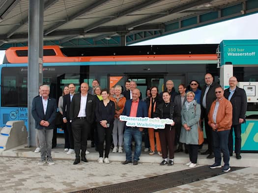 Gruppe von rund 25 Menschen vor einem Wasserstoffbus an einer Tankstelle mit Schild Wasserstoff echt grün aus Waiblingen