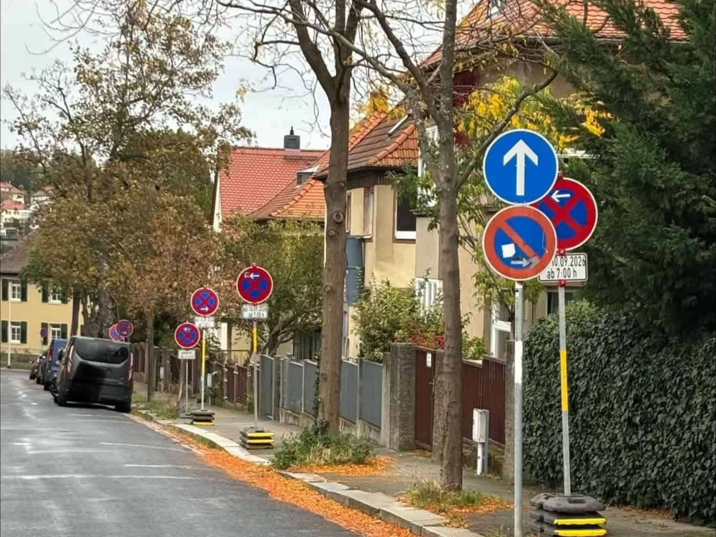 Wohnstraße am Ratsweinberg in Meißen mit vielen mobilen Halteverbotsschildern am Gehwegrand, Herbstlaub auf der Fahrbahn