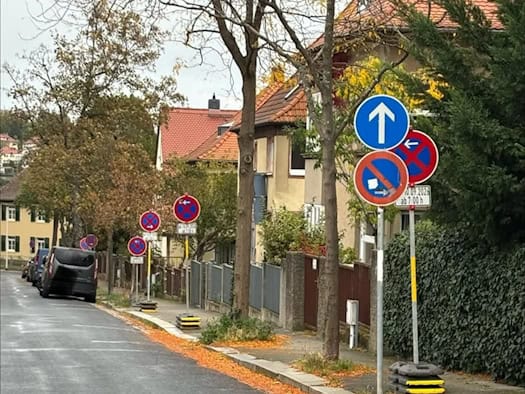 Wohnstraße am Ratsweinberg in Meißen mit vielen mobilen Halteverbotsschildern am Gehwegrand, Herbstlaub auf der Fahrbahn
