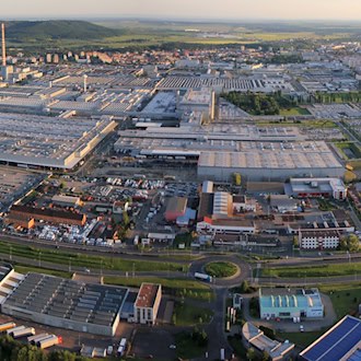 Luftaufnahme des weitläufigen Škoda-Werks in Mladá Boleslav mit Produktionshallen, Parkplätzen und angrenzenden Wohngebäuden.