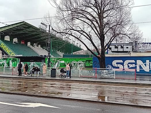 Blick von der Straßenbahnhaltestelle auf die grüne Tribüne und die Außenmauer des Stadions Ďolíček in Prag.