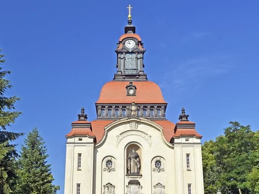 Die Kirche Moritzburg mit Kuppel, Uhrturm und Figur über dem Portal vor blauem Himmel.