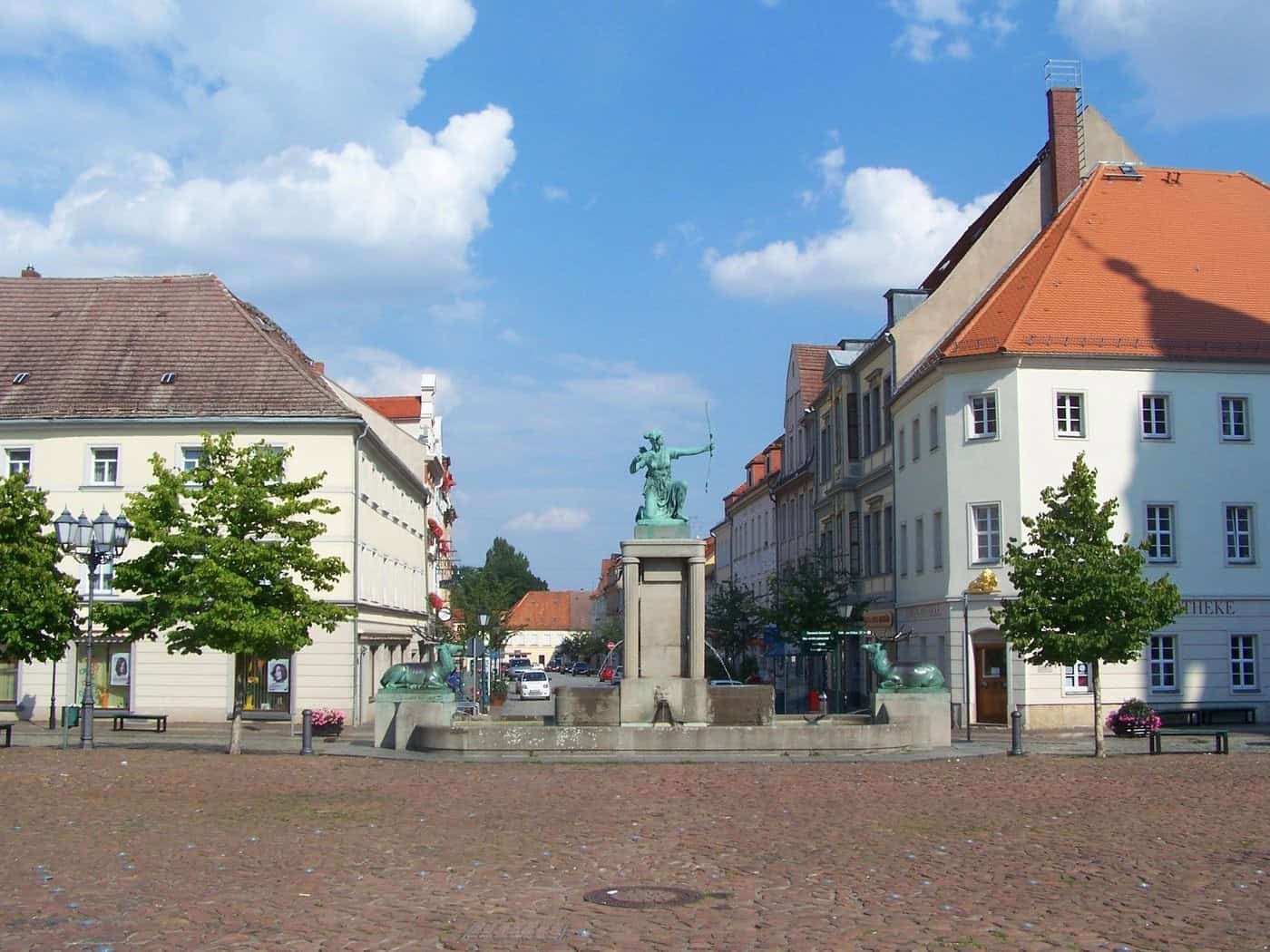 Hauptmarkt Großenhain mit Dianabrunnen und historischen Häusern bei blauem Himmel