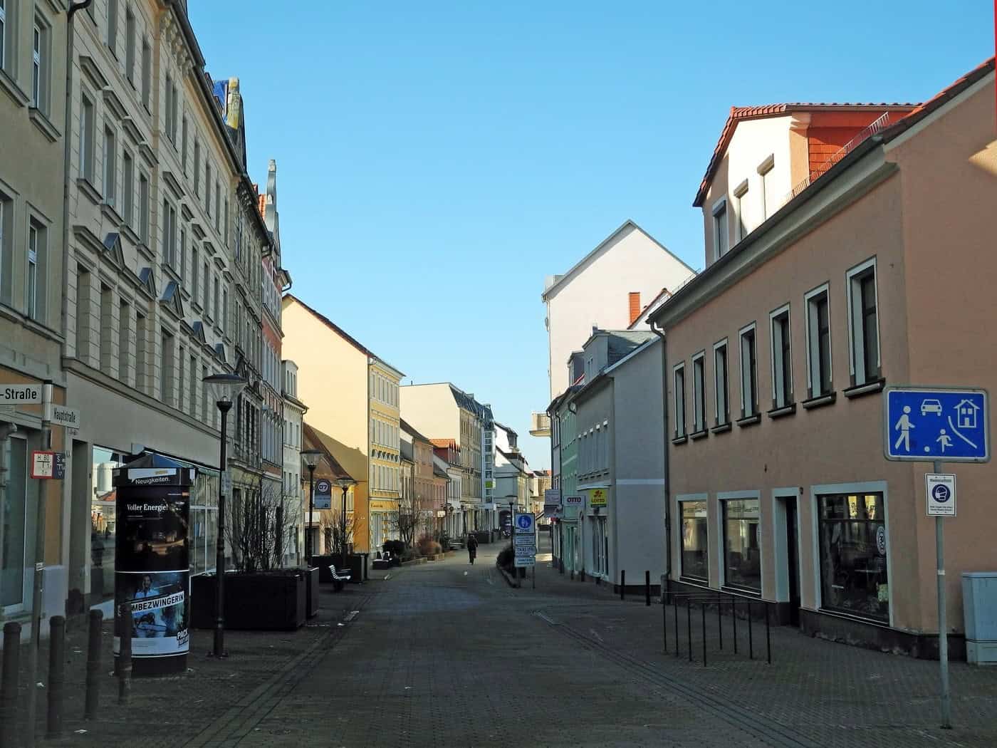 Fußgängerzone Hauptstraße in Riesa mit Altbauten und Geschäften bei blauem Himmel
