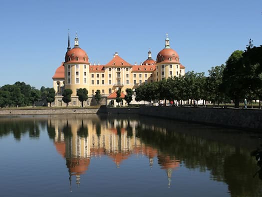 Schloss Moritzburg mit gelber Fassade und vier Ecktürmen, gespiegelt im Schlossteich