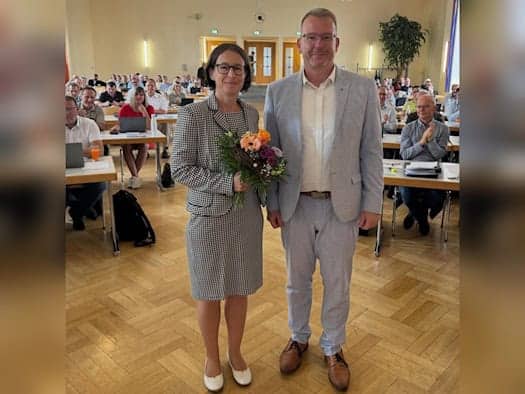 Pia Weißenberg mit Blumenstrauß neben Landrat Sven Krüger im Sitzungssaal des Kreistags