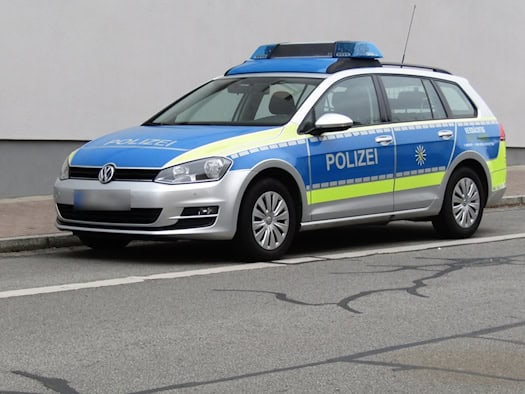 Blau-silberner Streifenwagen der Polizei Sachsen mit Blaulicht auf dem Dach am Straßenrand