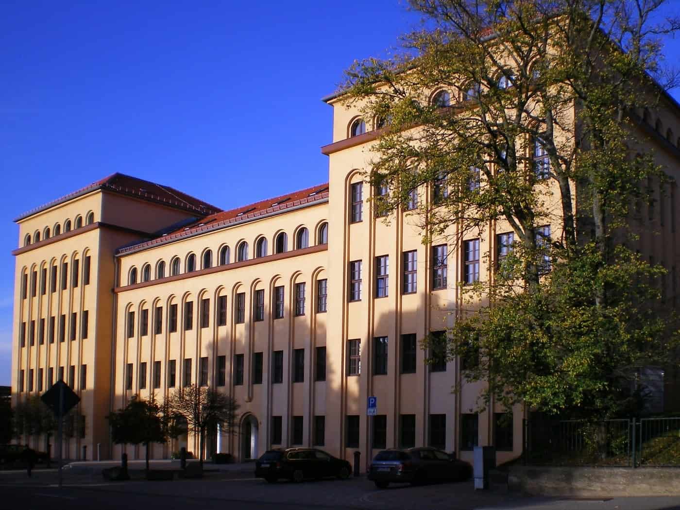 Mehrstöckiges ockerfarbenes Gebäude des Landratsamts Freiberg mit Rundbogenfenstern unter blauem Himmel
