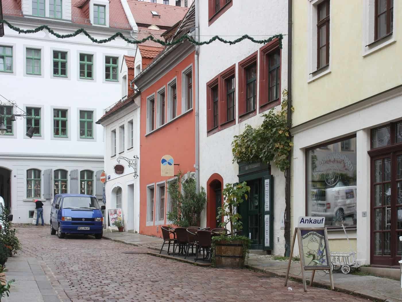 Gepflasterte Burgstraße in Meißen mit bunten Altstadthäusern und Café-Stühlen