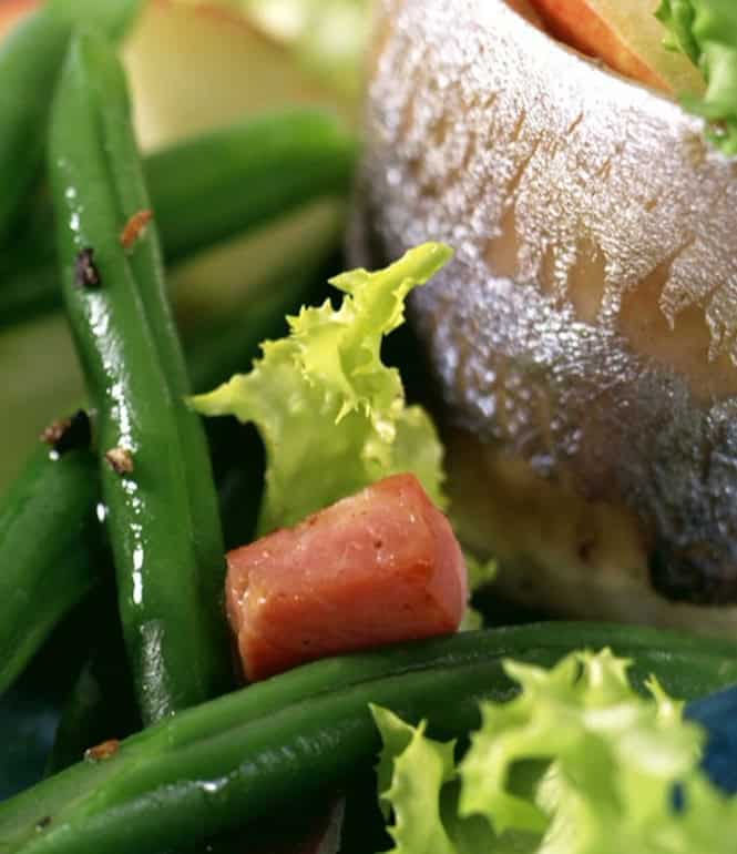 Fertiges Gericht Matjes mit grünem Bohnensalat und Pellkartoffeln angerichtet auf einem Teller