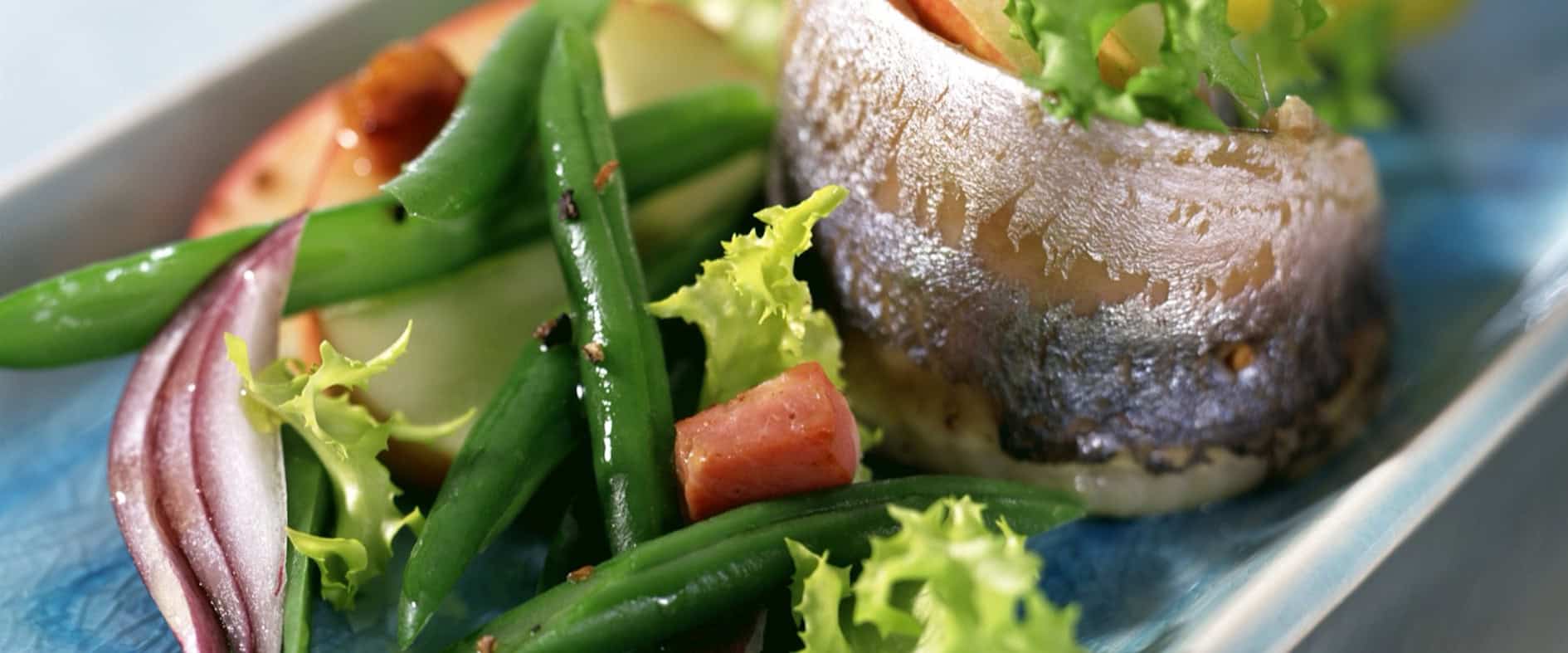 Fertiges Gericht Matjes mit grünem Bohnensalat und Pellkartoffeln angerichtet auf einem Teller
