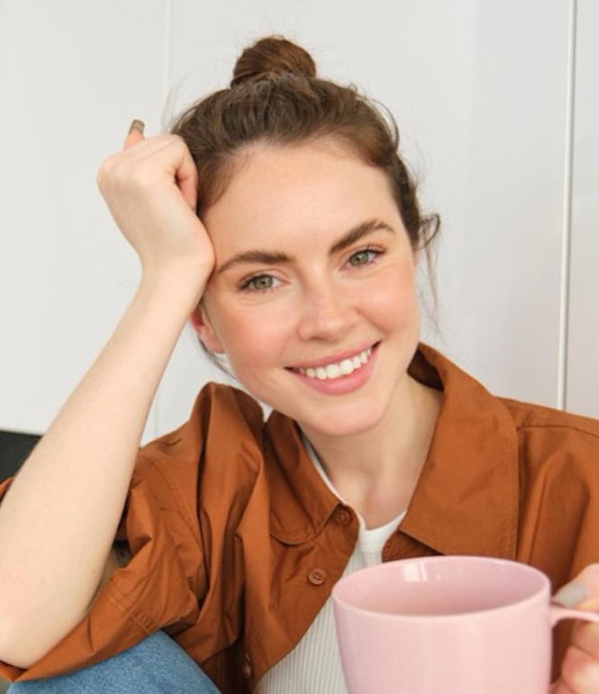 Junge Frau trinkt entspannt ihren Kaffee am Morgen in der Küche.