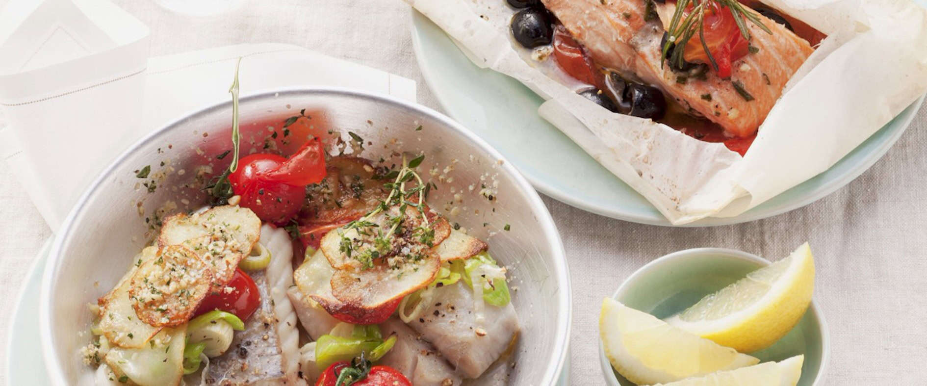 Im Ofen gegarter Lachs mit Tomaten und Oliven im Pergamentpapier Gedeckter Tisch mit fertigem Gericht Lachs im Pergamentpapier