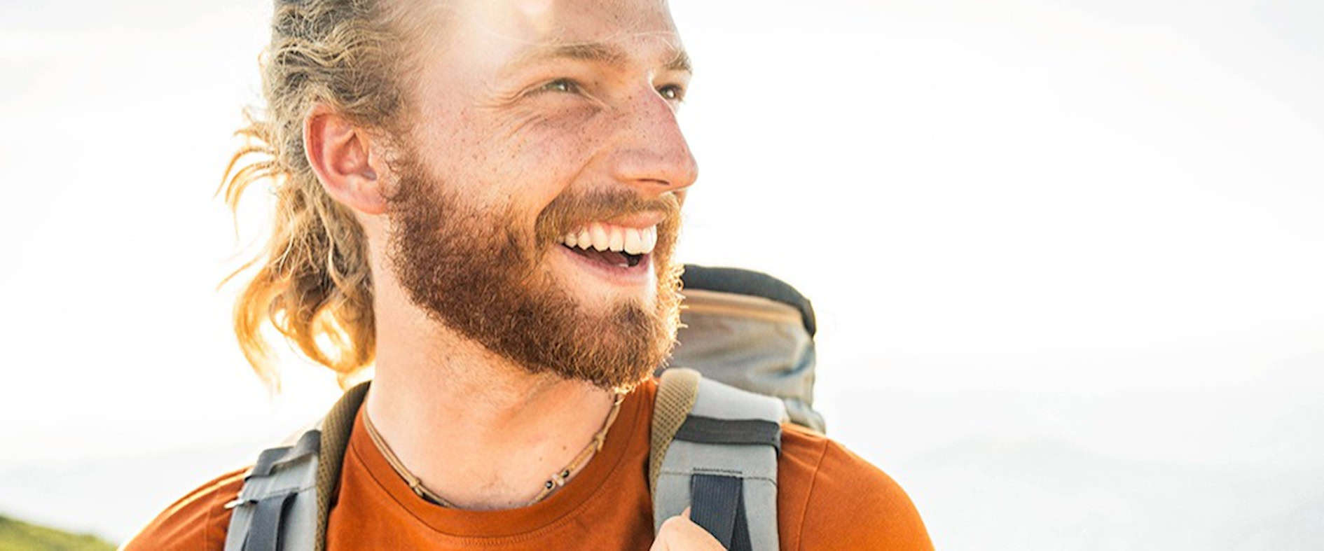 Lachender Wanderer mit Rucksack in der Sonne – Symbol für Lebensfreude und kleine Glücksmomente in der Natur