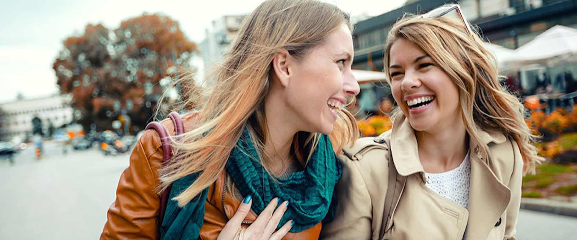Zwei fröhliche Frauen beim Stadtbummel, lachen und genießen den Moment – Symbolbild für Lebensfreude, Wohlstand und alltägliches Glück.