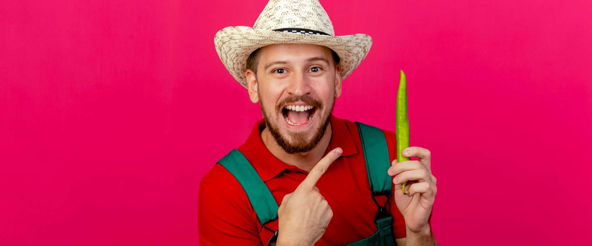 Mann mit Strohhut hält grüne Chili in der Hand und zeigt darauf – Symbolbild für Freude an eigener Ernte