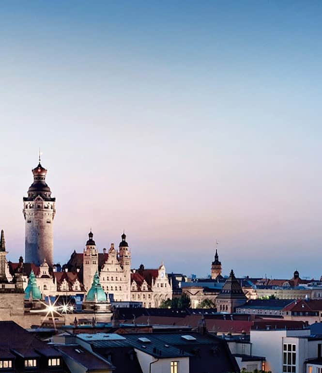 Panoramablick auf Leipzigs Innenstadt mit historischen Gebäuden und moderner Architektur im Abendlicht.