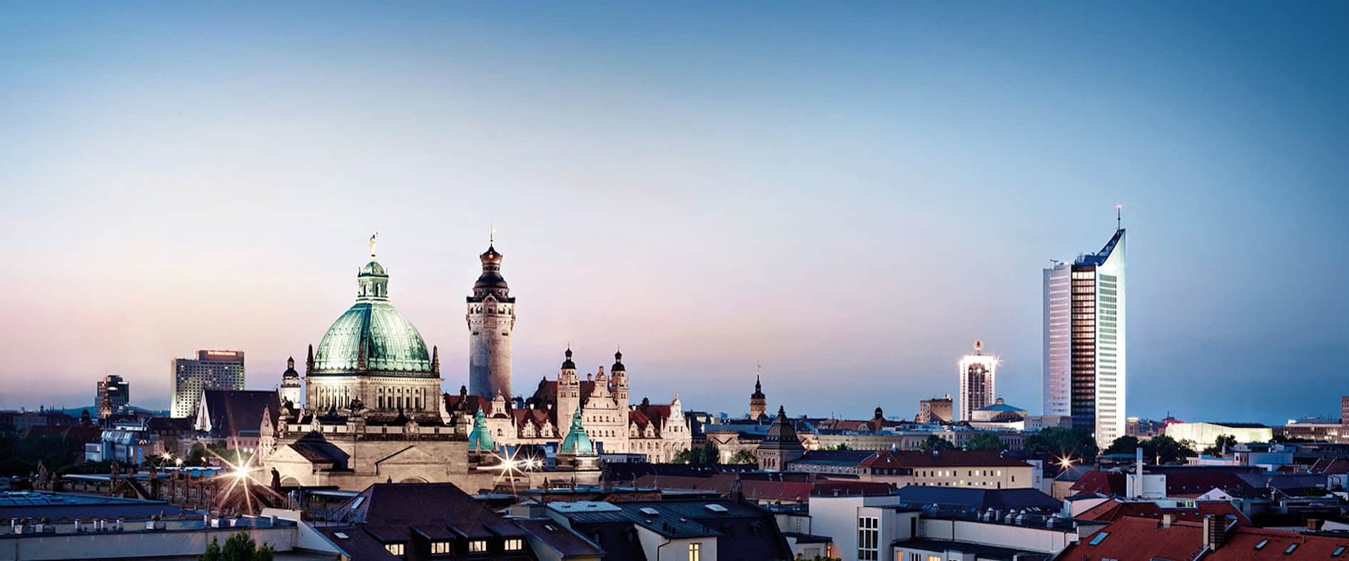 Panoramablick auf Leipzigs Innenstadt mit historischen Gebäuden und moderner Architektur im Abendlicht.