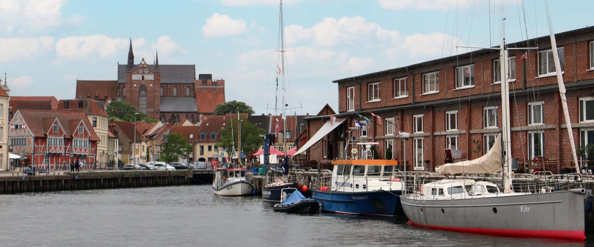 Alter Schwede! Auf Spurensuche in Wismar Alter Hafen von Wismar mit Blick auf historische Backsteingebäude und die St.-Georgen-Kirche im Hintergrund.