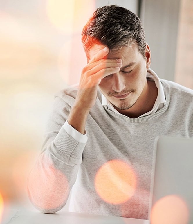 Mann mit Hand an der Stirn sitzt nachdenklich am Laptop – Symbolbild für Verlust und Pech.
