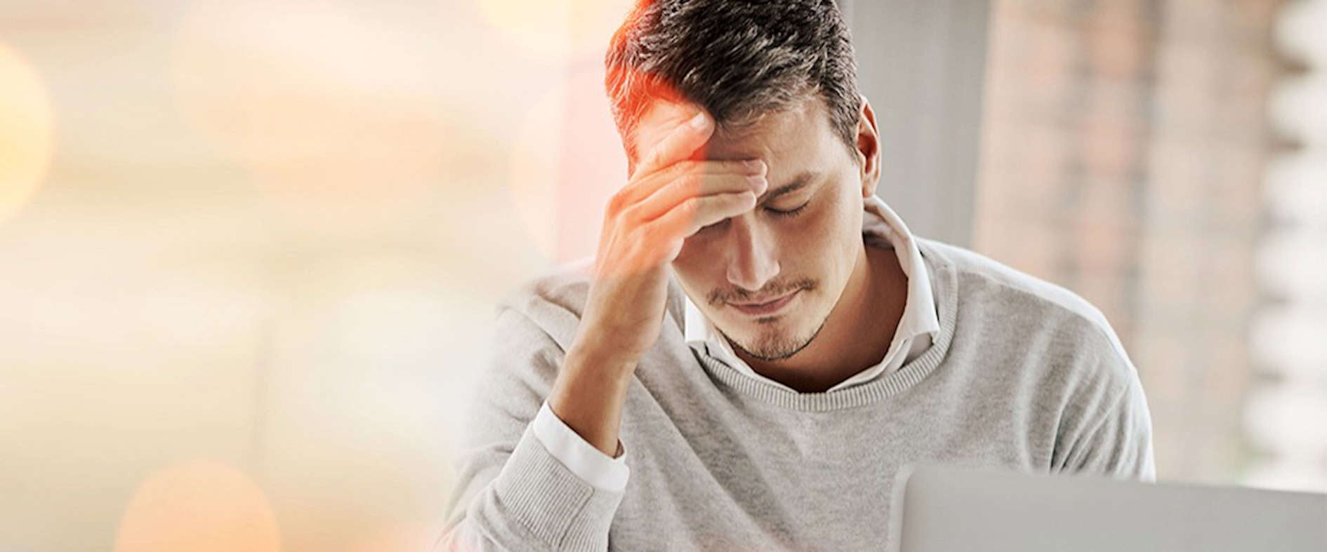 Mann mit Hand an der Stirn sitzt nachdenklich am Laptop – Symbolbild für Verlust und Pech.