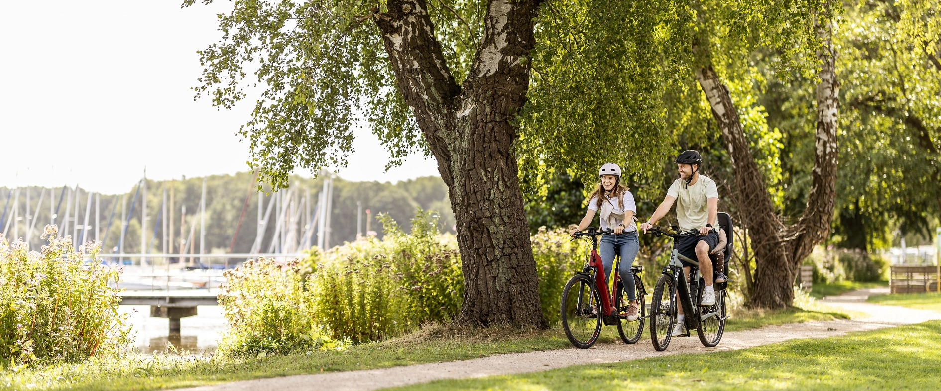 Zwei Radfahrende unterwegs auf einem Radwanderweg in Schleswig-Holstein, umgeben von Natur.