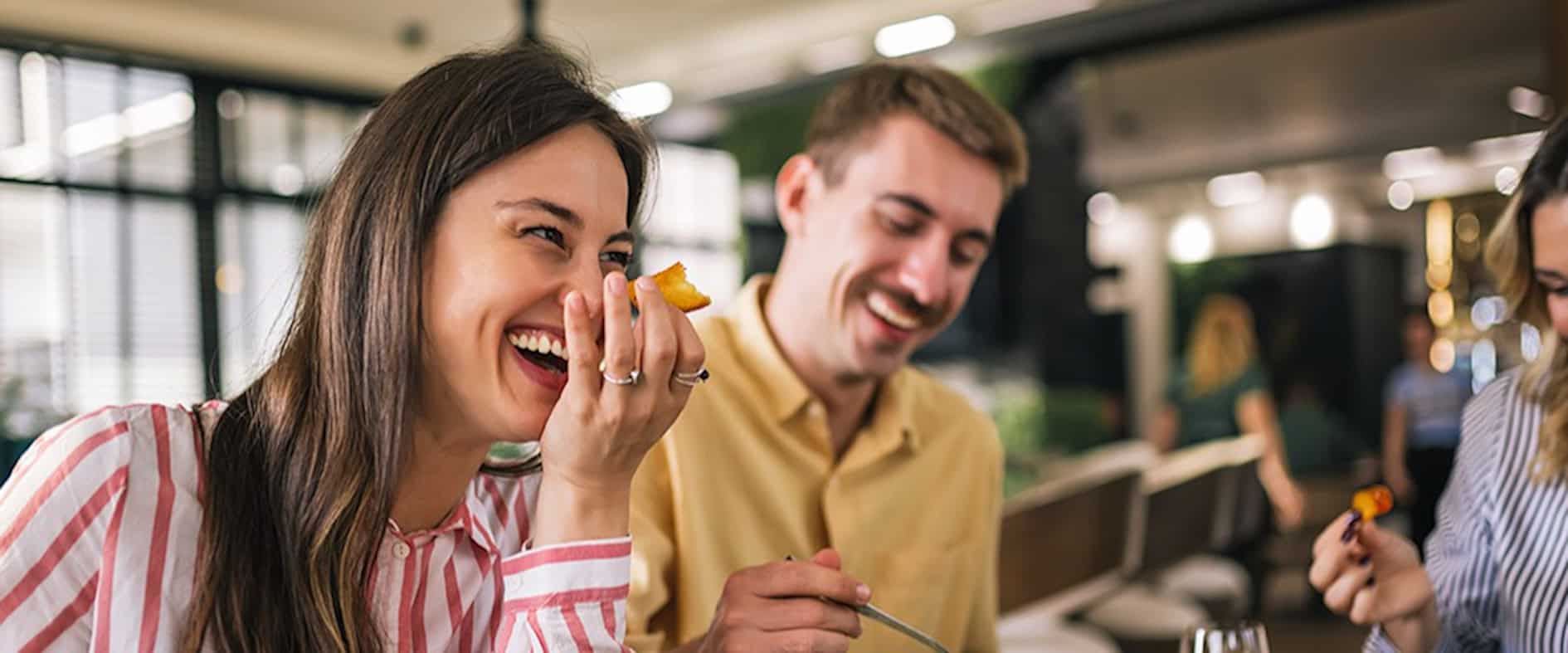 Zwei Menschen lachen gemeinsam beim Essen in einem Restaurant – ein Beispiel für alltägliche Glücksmomente.