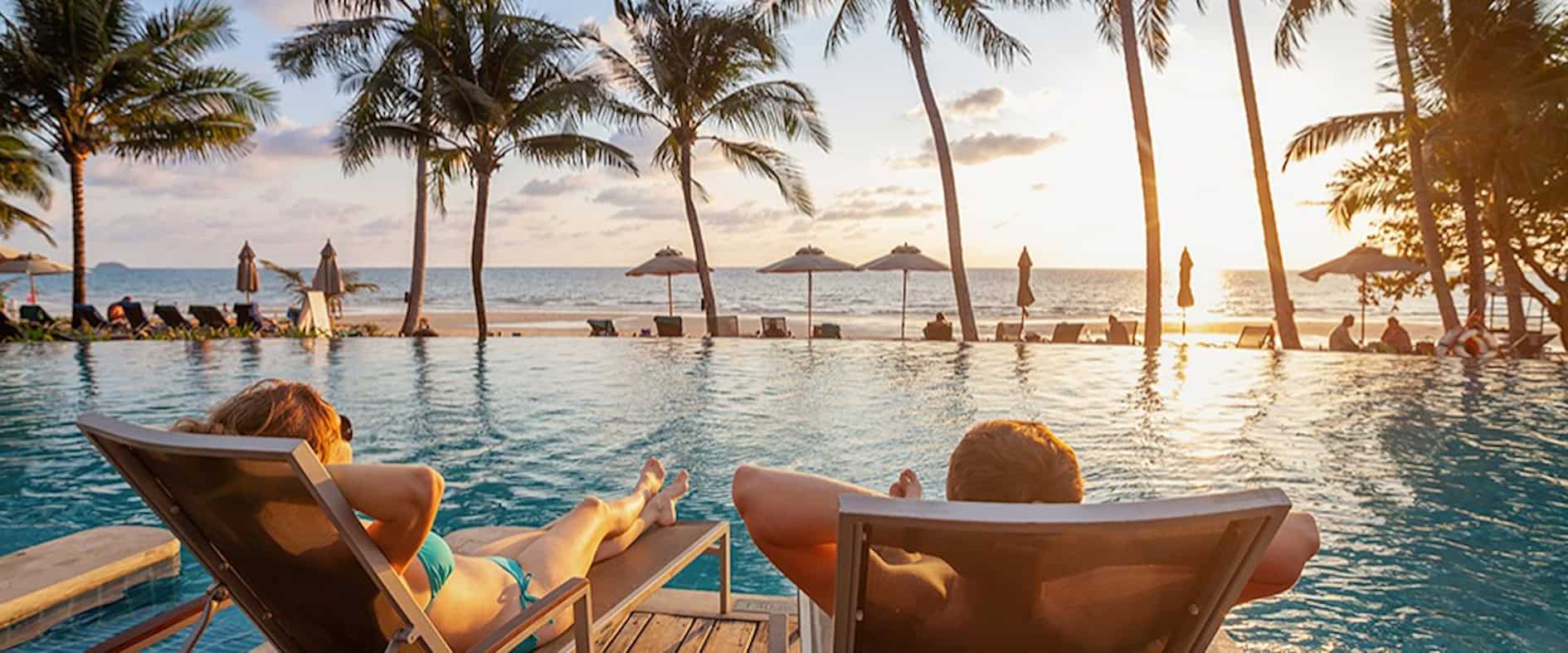 Paar entspannt am Pool mit Meerblick bei Sonnenuntergang, Blue Mind Theorie.