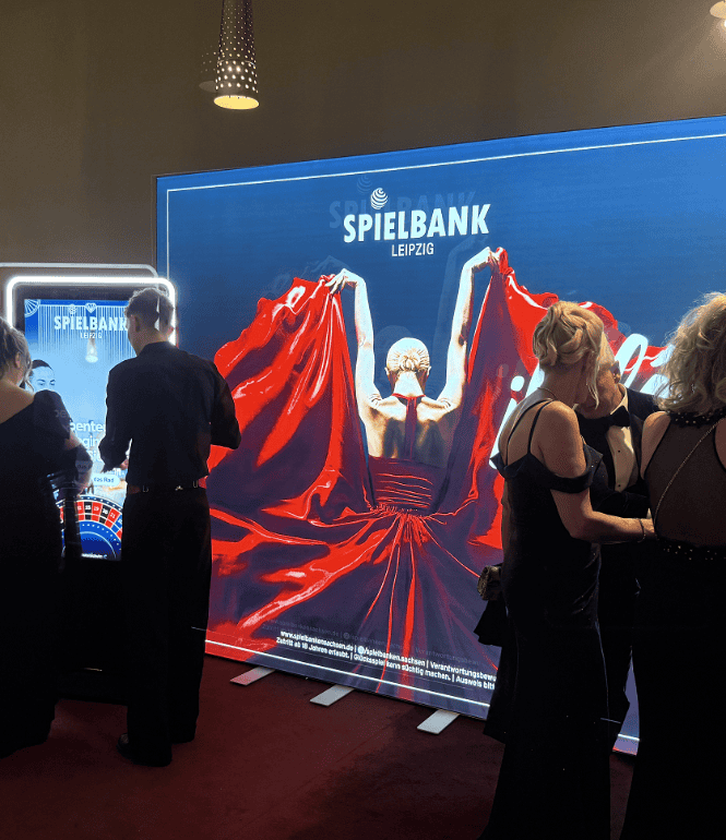Besucher in Abendgarderobe vor dem „¡Olé!“-Leuchtmotiv der Spielbank Leipzig beim Opernball 2025.