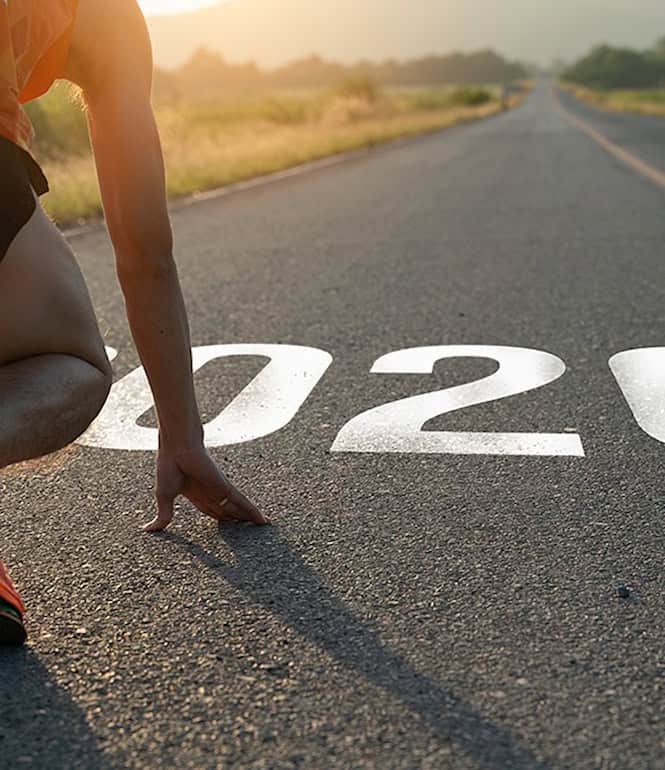 Athlet in Startposition auf einer Straße mit der Jahreszahl 2026 auf dem Asphalt.