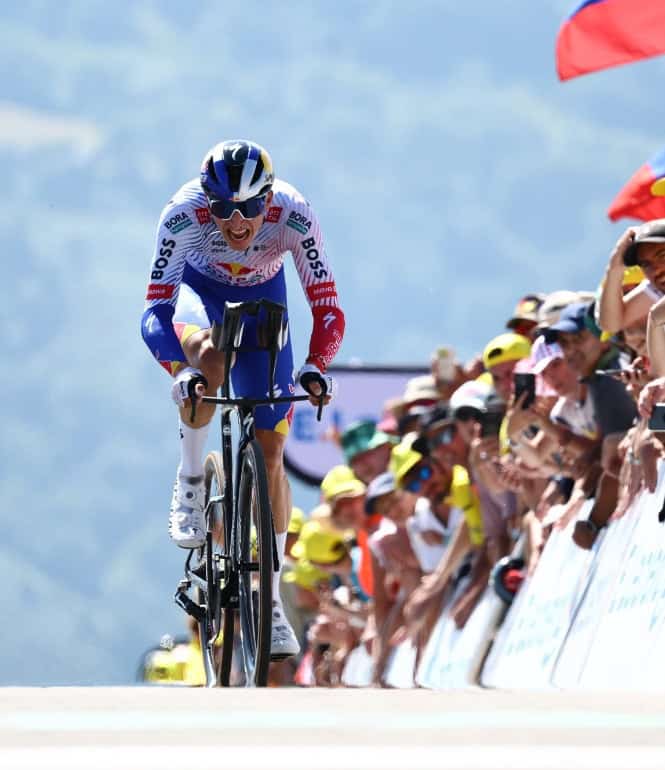 Der deutsche Radprofi Florian Lipowitz kämpft sich bei der Tour de France einen Anstieg hinauf, angefeuert von jubelnden Zuschauern am Streckenrand.