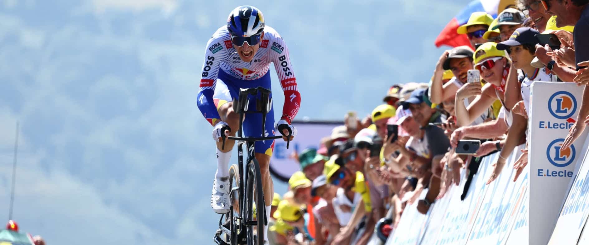 Der deutsche Radprofi Florian Lipowitz kämpft sich bei der Tour de France einen Anstieg hinauf, angefeuert von jubelnden Zuschauern am Streckenrand.