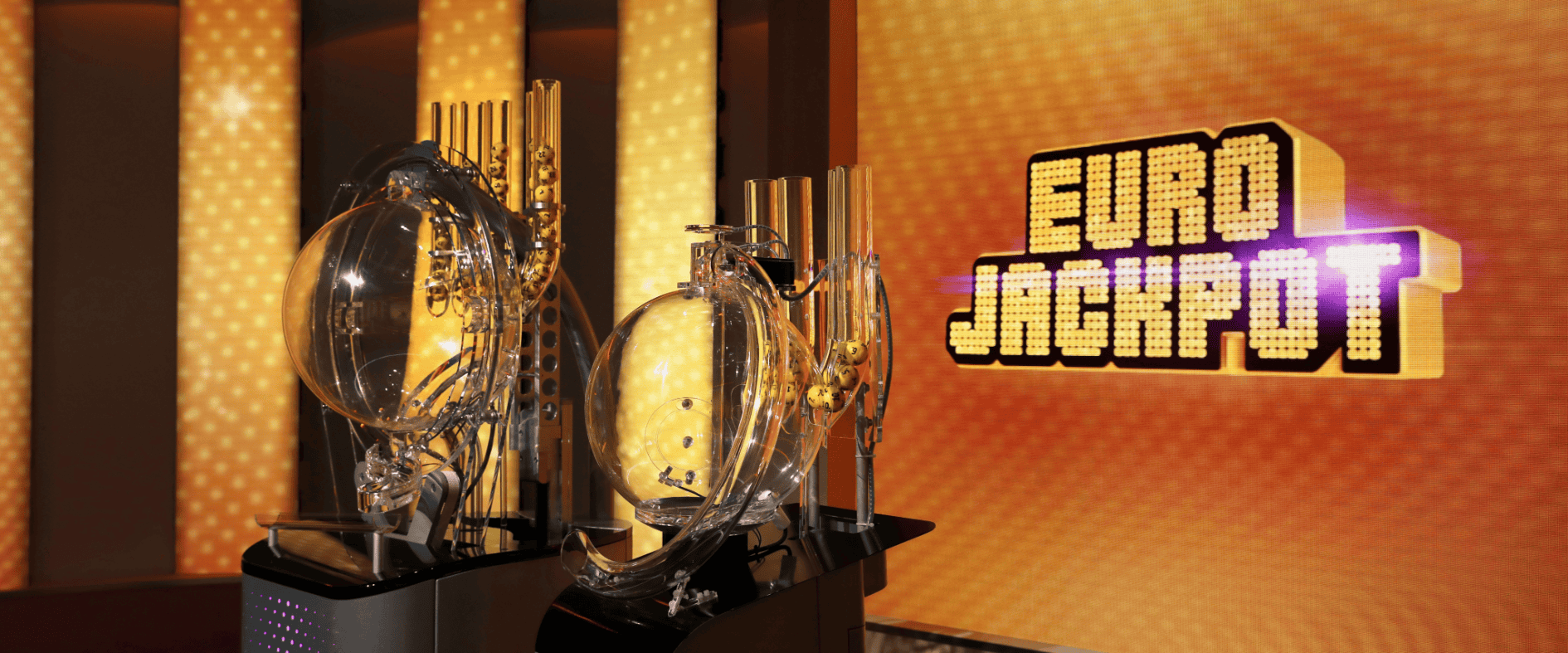 Ziehungsgeräte im Eurojackpot-Studio vor leuchtend gelbem Hintergrund mit Logo