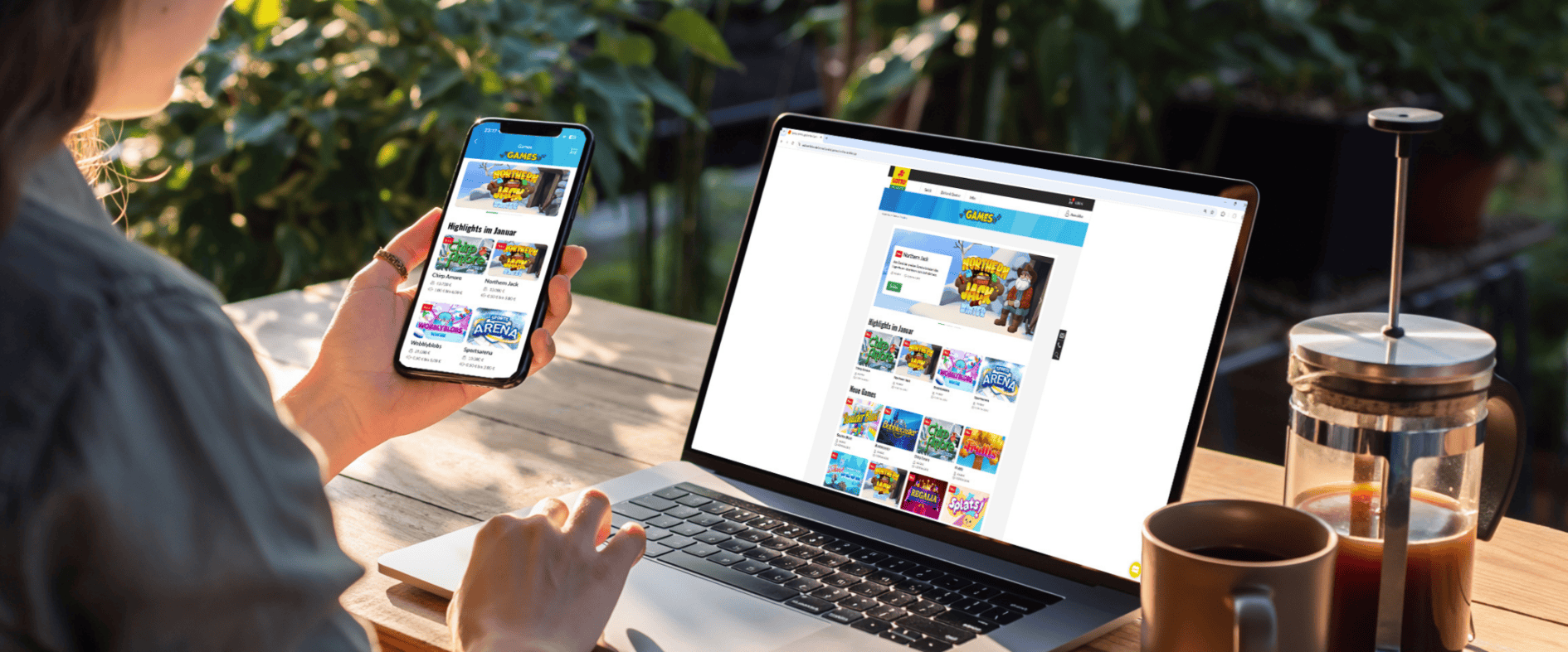 Frau nutzt Smartphone und Laptop im Garten, um die digitalen GAMES von Sachsenlotto zu spielen