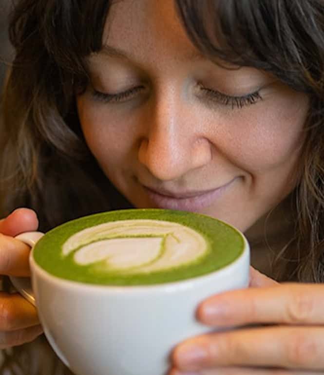 Frau genießt einen Matcha Latte mit Latte Art in einem Café als kleinen Alltagsluxus