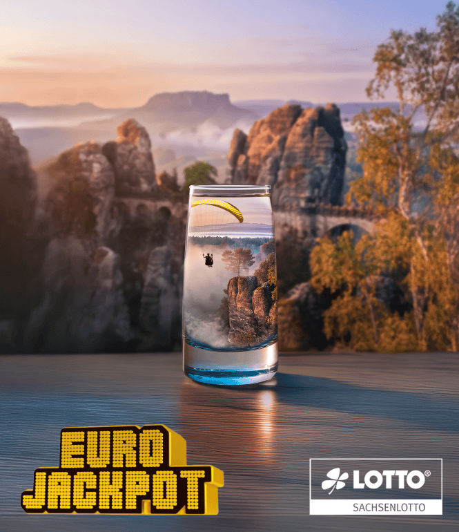 Eurojackpot Motiv von Sachsenlotto: Ein Gleitschirmflieger schwebt über einer Felsenlandschaft, gespiegelt in einem Glas vor der Sächsischen Schweiz.