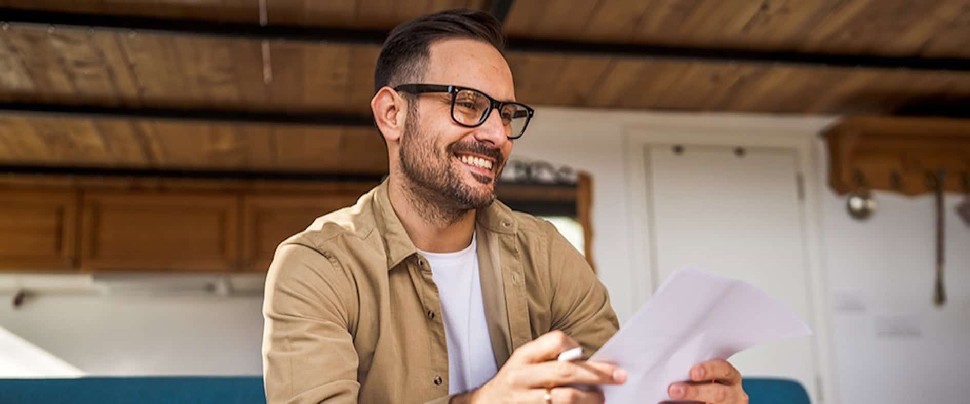 Lächelnder Mann liest einen Brief – ein Moment der Wertschätzung und des Glücks.
