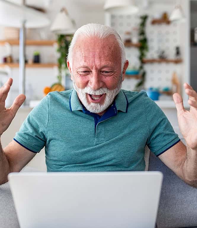 Begeisterter Rentner lachend vor dem Laptop – die pure Freude über einen unerwarteten Gewinn.