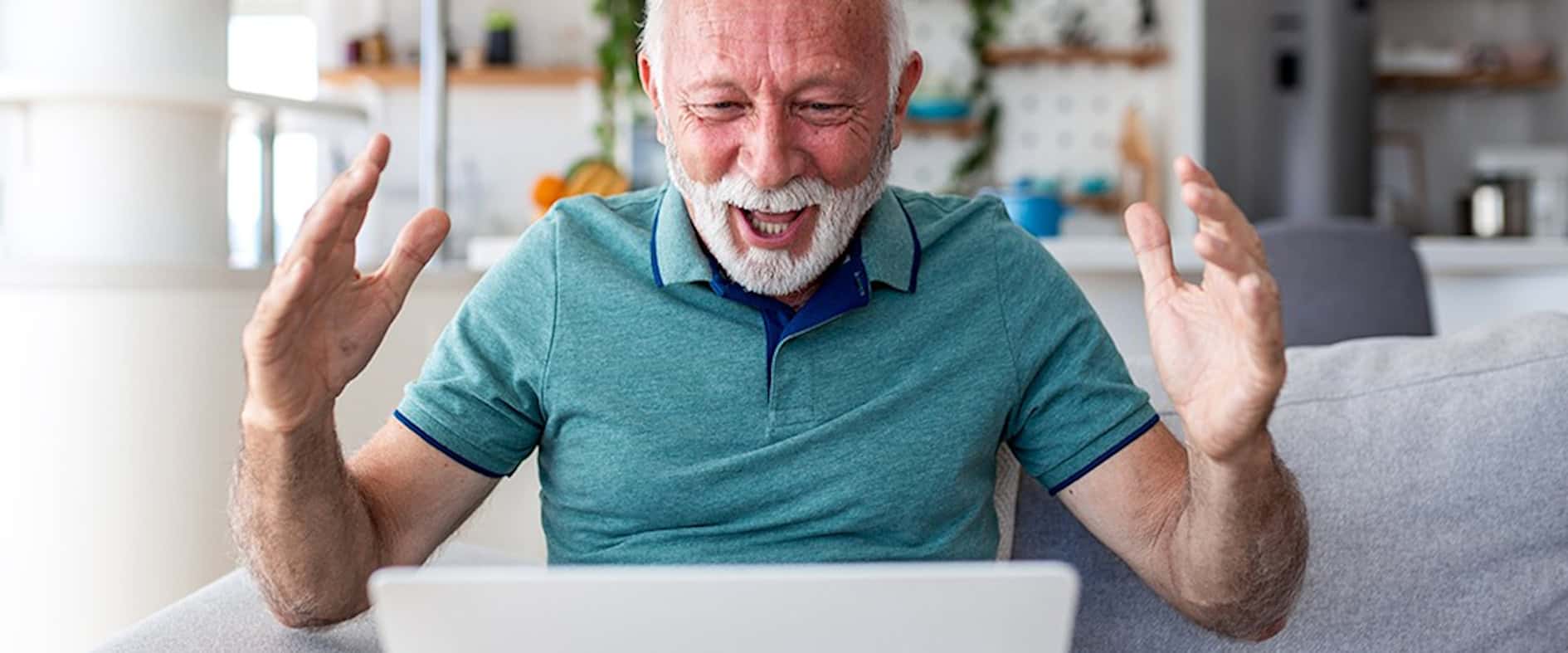 Begeisterter Rentner lachend vor dem Laptop – die pure Freude über einen unerwarteten Gewinn.
