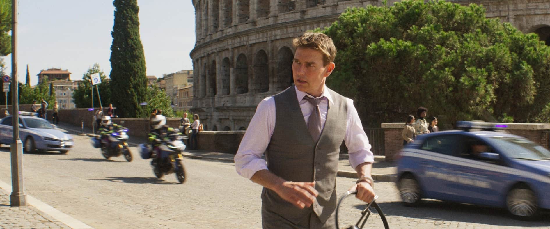 Tom Cruise als Ethan Hunt in einer Action-Szene vor dem Kolosseum in Rom, mit Motorrädern und Autos im Hintergrund – Szene aus ‚Mission: Impossible – Dead Reckoning, Teil Eins‘