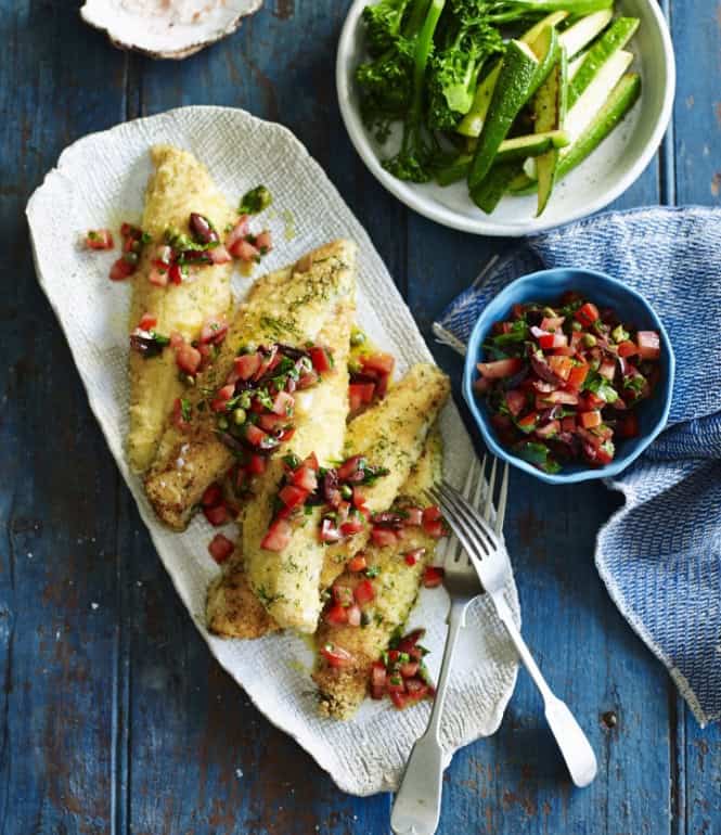 Fischfilets mit Grießkruste und Tomaten-Oliven-Salsa auf einem ovalen Teller, serviert mit Brokkoli und Zucchini sowie einer Schüssel Salsa.