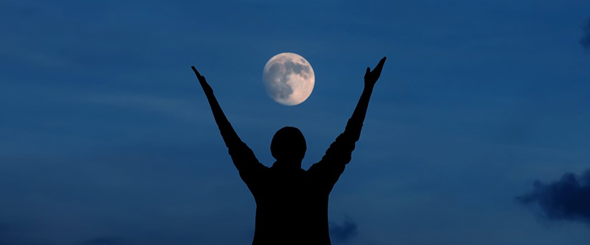 Silhouette einer Person mit erhobenen Armen vor Vollmond