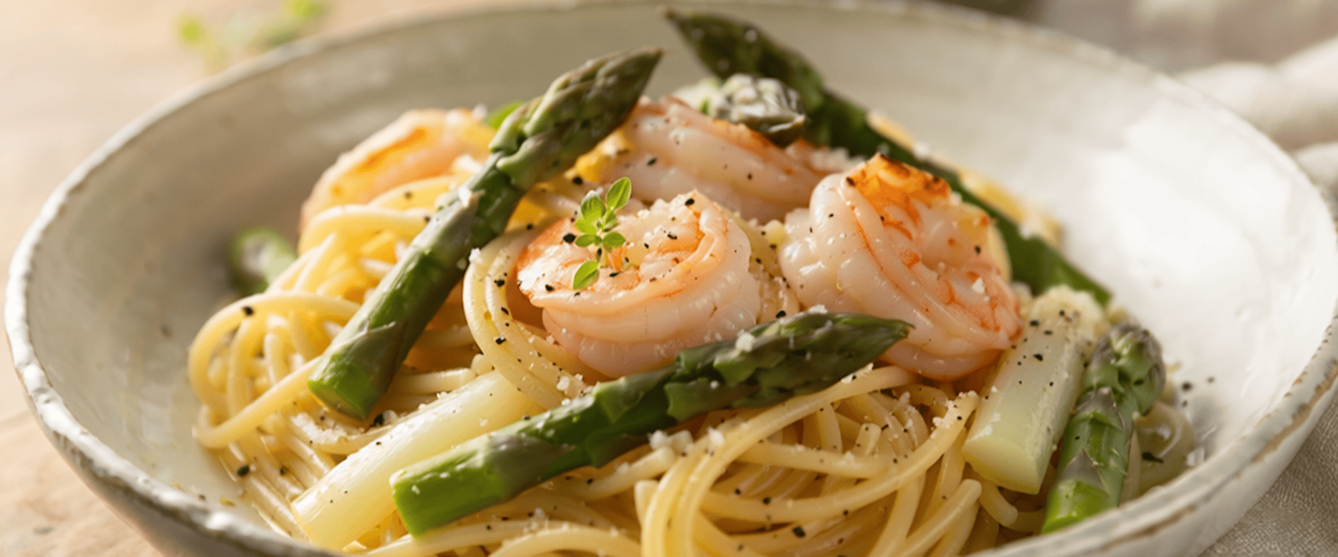 Spaghetti mit grünem Spargel und Garnelen in einer Schüssel, garniert mit Thymian.