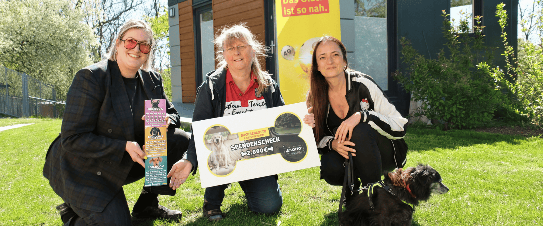 Magdalena Bartmann von Sachsenlotto übergibt gemeinsam mit Kristin Hardt einen 2.000-Euro-Spendenscheck aus der Lucky Dog Aktion an Sabine Kaden vom Tierheim Gröbern. Bartmann hält Lucky Dog Rubbellose in der Hand.