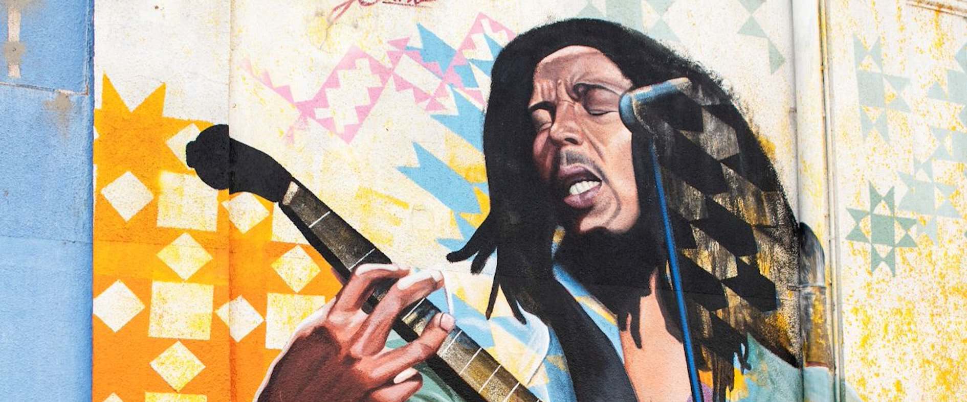 Graffiti von Bob Marley mit Gitarre und Mikrofon an einer Wand