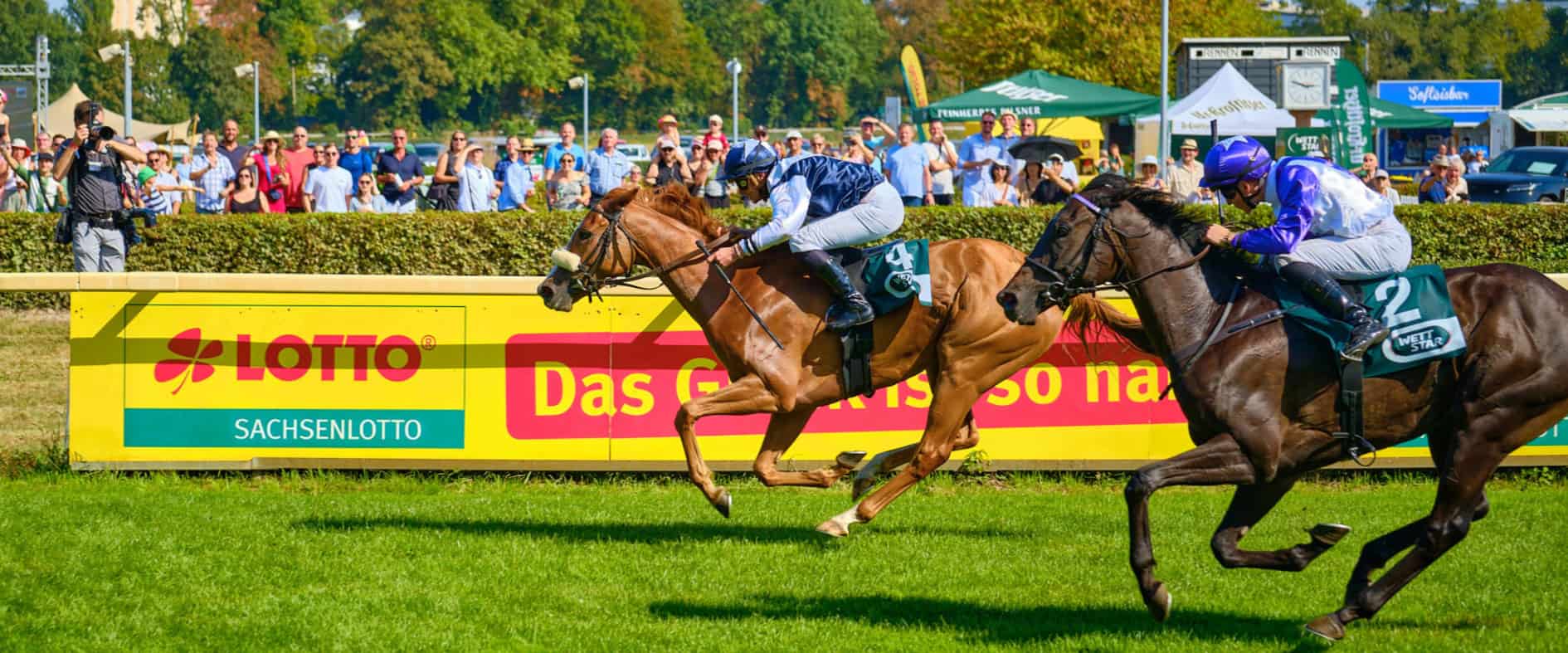 Galopprennen beim Sachsenlotto Cup mit zwei Jockeys auf der Zielgeraden vor Publikum